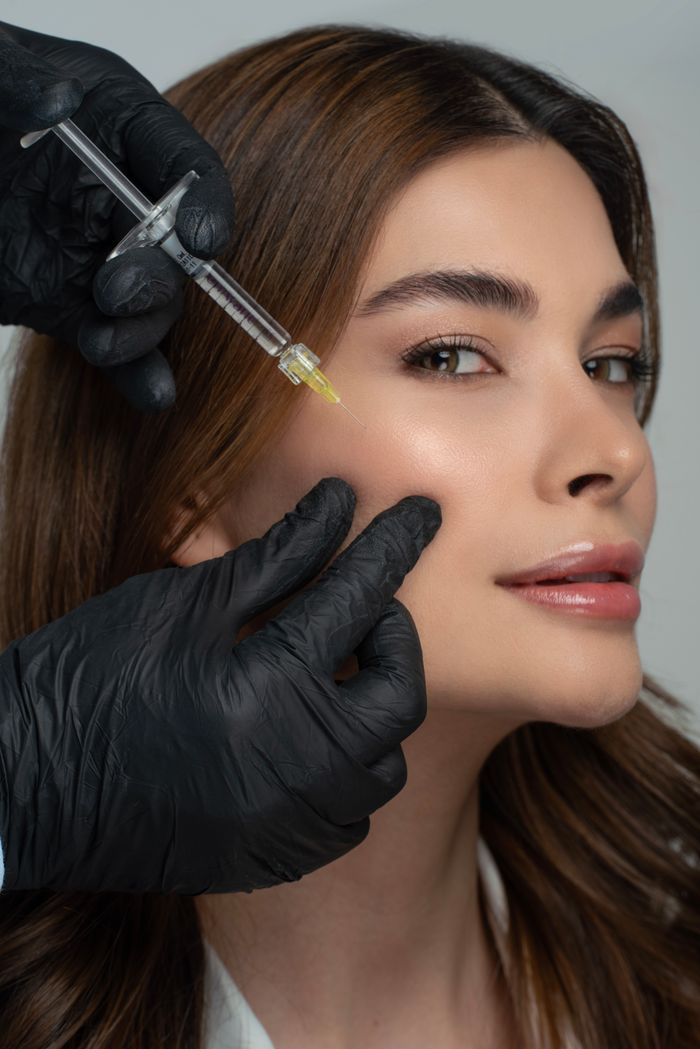 Close-up of a woman receiving a cosmetic facial injection from a professional wearing gloves.